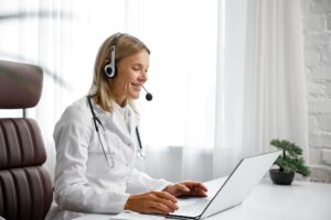 Telemedicine. Headshot portrait of smiling female doctor in headphones looking at camera. A female